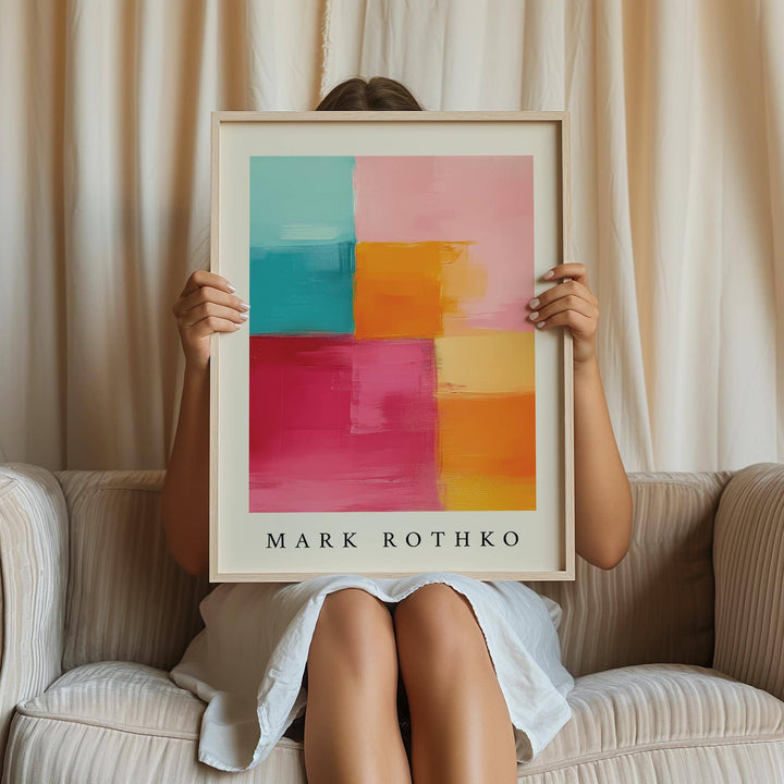 Framed Abstract Art with Pink showing colourful blocks held by person sitting on striped sofa