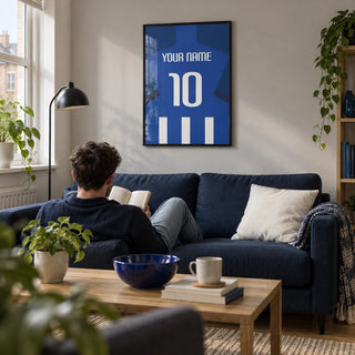 Football Shirt Poster in Blue and White Stripes with Dark Blue Sleeves, framed on the wall of a compact modern living room in a football fan’s first UK flat (22-28)
