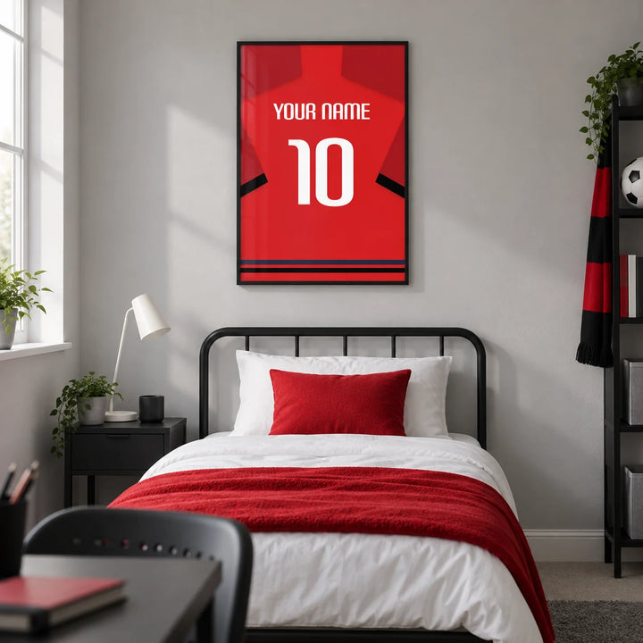 Football Shirt Poster in Red with Black Sleeve Bands, framed on the wall of a modern football-loving teenager's single bedroom (13-17) in a UK family home with a pale grey wall