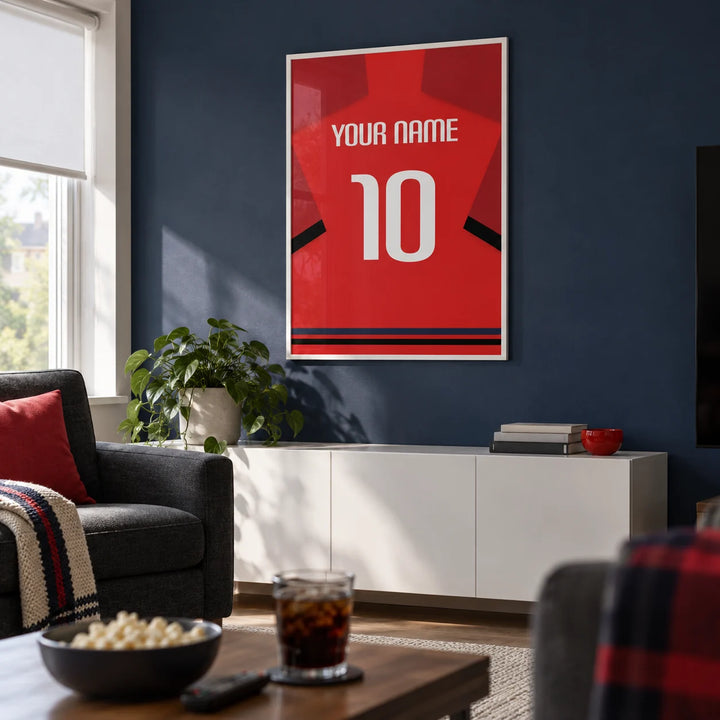 Football Shirt Poster in Red with Black Sleeve Bands, framed on the wall of a modern football-watching snug in a UK semi-detached home with a muted navy wall in a living room