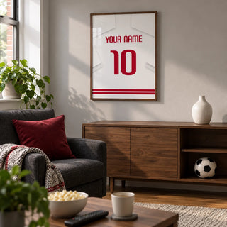 Football Shirt Poster in White with Red Number, framed on the wall of a small football-watching snug in a UK terraced house with a soft grey wall and walnut furniture in a living room