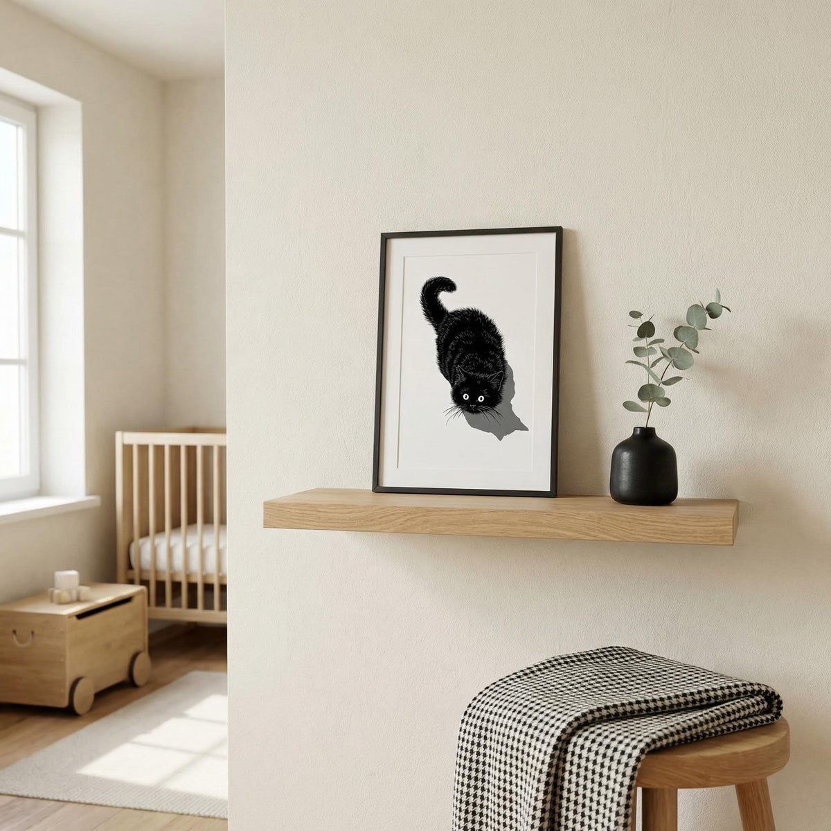 Nursery room with a framed black and white cat print on a wooden shelf.