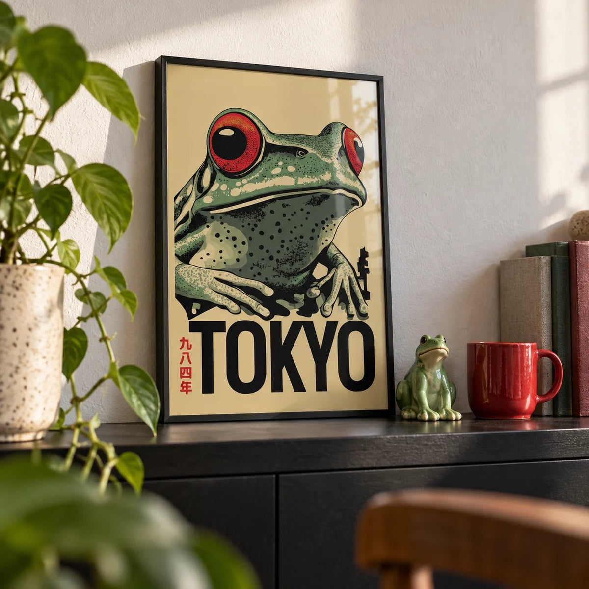 Frog Poster, a small A4 framed print leaning on a black shelf in a living room