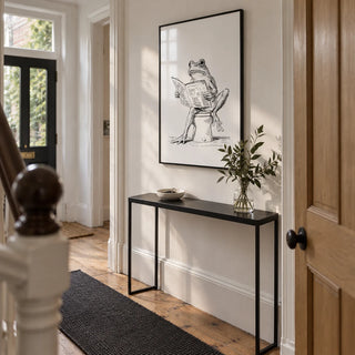 Reading Frog Art Print, framed on the wall of a narrow entrance hallway in a characterful UK terrace with white walls and restored timber floorboards