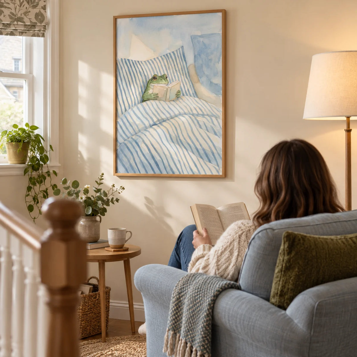 Frog Reading In Bed Print, framed on the wall of a cosy landing reading corner in a UK family home with a warm cream wall in a living room
