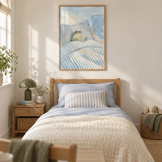 Frog Reading In Bed Print, framed on the wall of a gentle storybook single bedroom in a UK family home with a warm white wall and pale oak floor