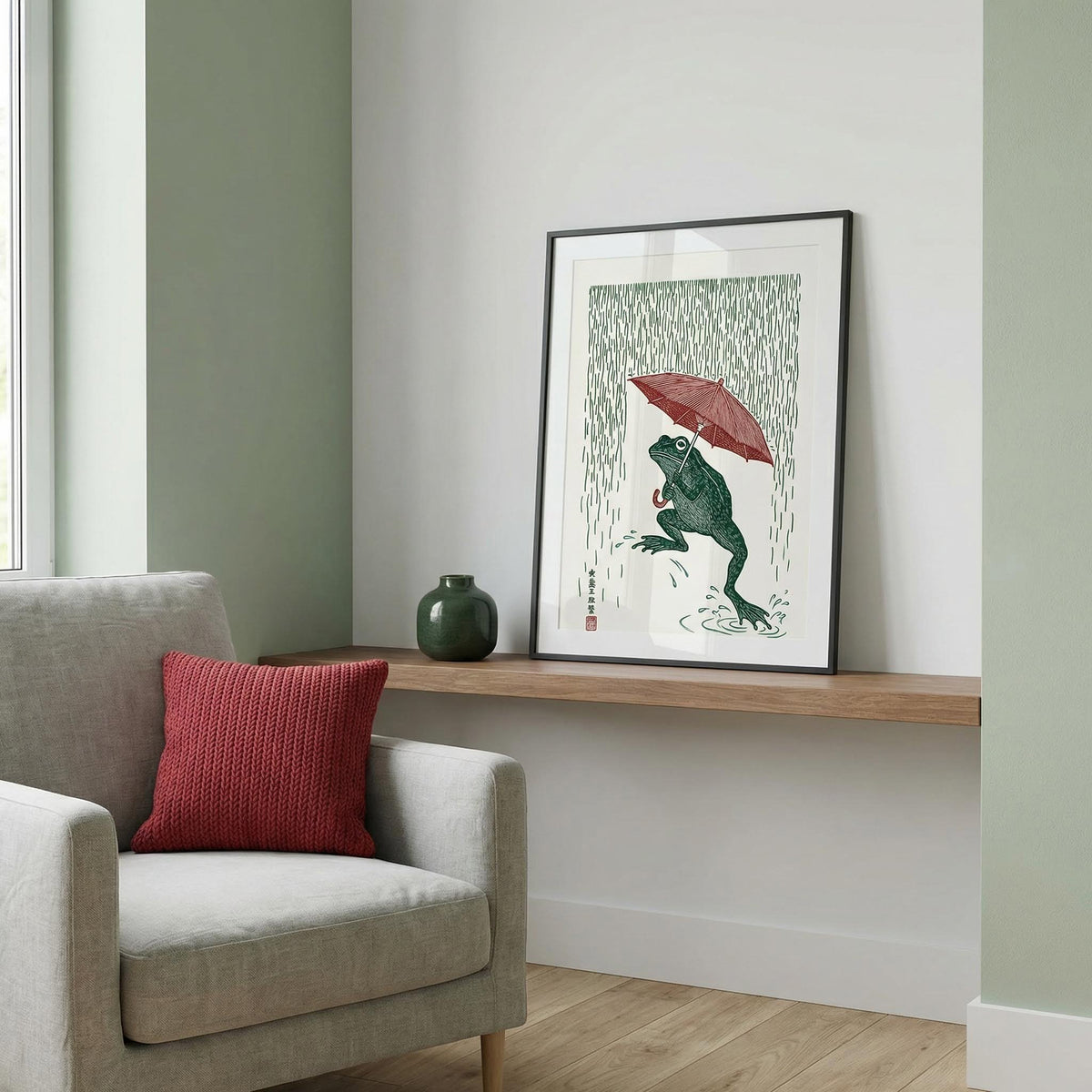 Framed artwork of a frog holding an umbrella on a wall above a sofa with a red pillow.