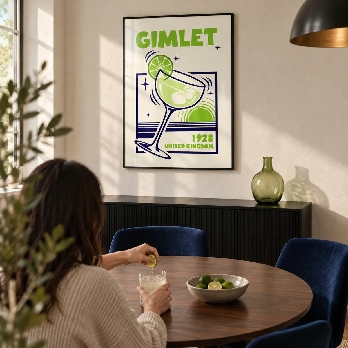 Gimlet Cocktail Poster, framed on the wall of a modern dining room in a UK home with an ivory plaster wall and a round walnut dining table