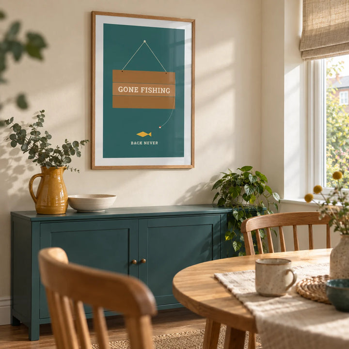 Gone Fishing Poster, framed on the wall of a bright dining nook in a modest UK flat with a cream wall and a small round oak table