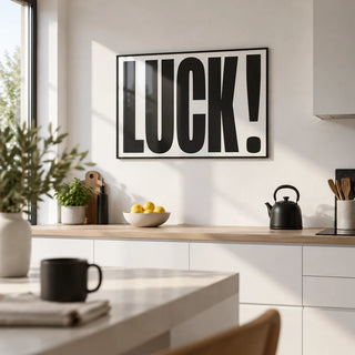 Good Luck Print, framed on the wall of a modern kitchen with white units and a white wall