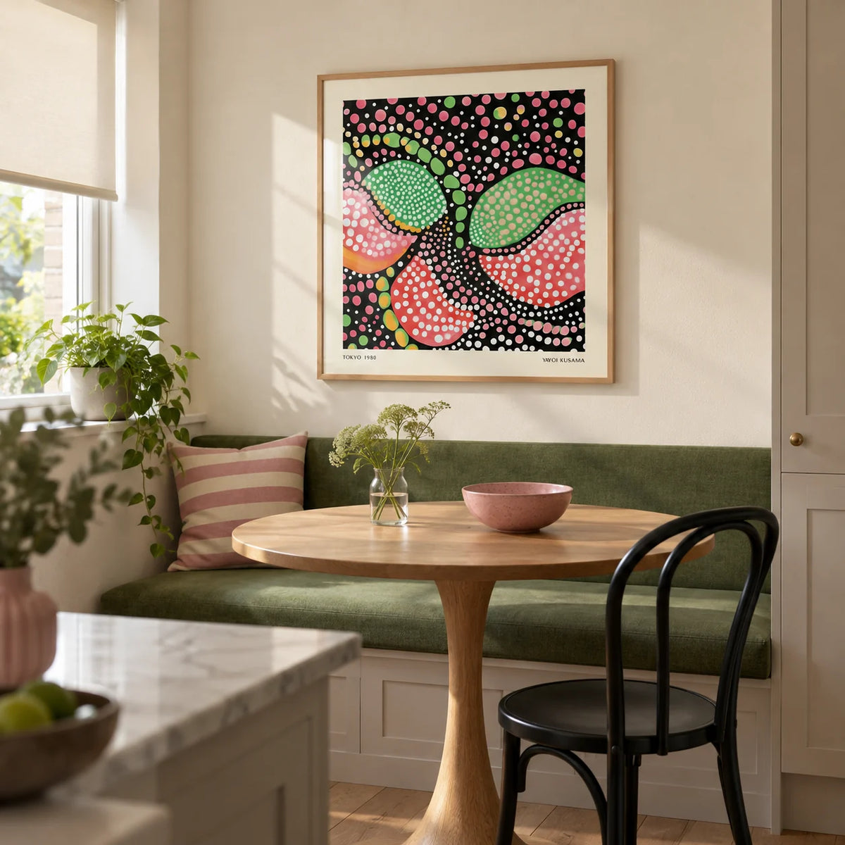 Green Pink Art, framed on the wall of a compact breakfast nook in a renovated UK kitchen with a cream wall and a built-in bench upholstered in solid green
