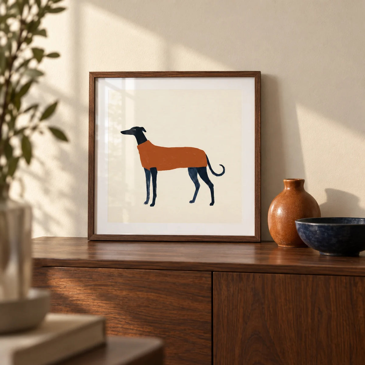 Greyhound Art Print, a small A4 framed print leaning on a walnut sideboard in a living room