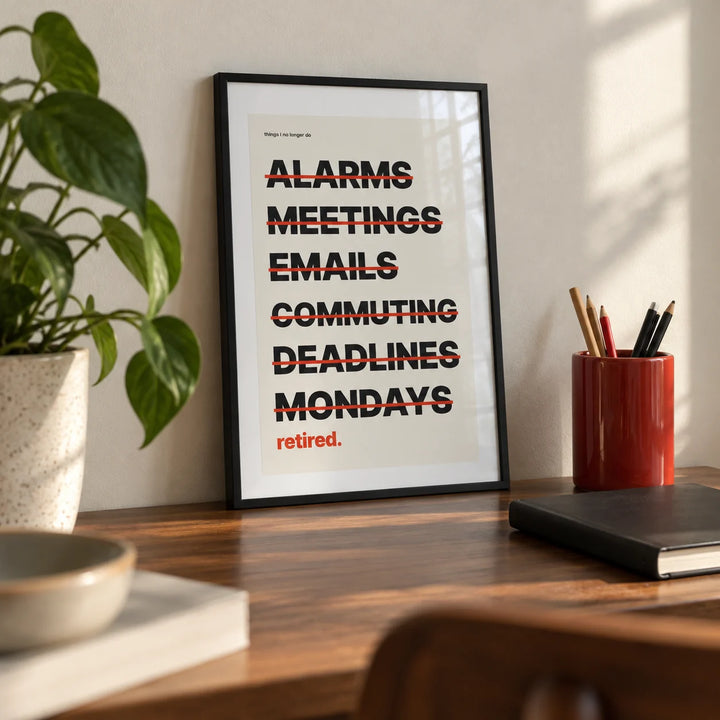 Happy Retirement Poster, a small A4 framed print leaning on a walnut desk