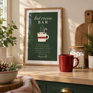 Hot Cocoa Bar Print, a small A4 framed print leaning on a pale oak kitchen worktop