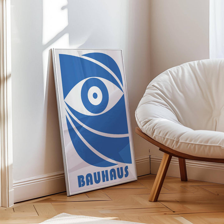 Print leaning on floor with blue stylised eye and typographic elements near a white cushioned chair