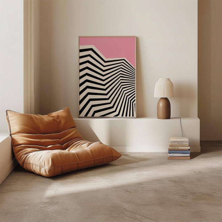 Wavy wall art with black and white zigzag pattern and pink background leaning on a white shelf next to a brown lamp and stack of books