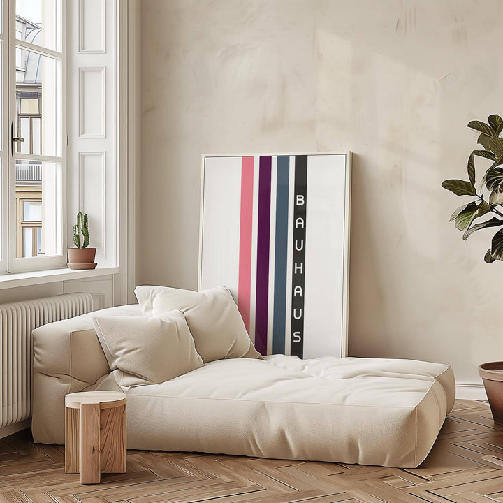 Geometric Art Wall print with vertical stripes in pink, purple and grey leaning above a beige sofa with cushions