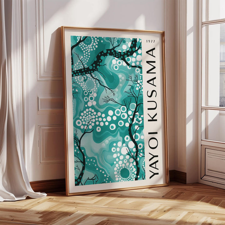 Print of teal wall decor with abstract branches and white dots leaning near a window with curtains