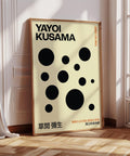 Minimalist Yayoi Kusama poster with beige background and black polka dots.