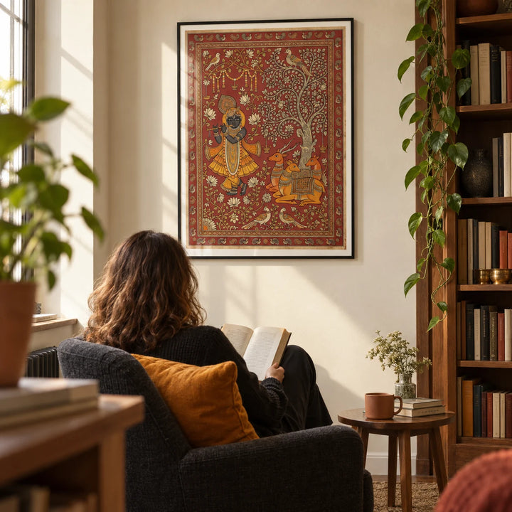 Indian Folk Art Print, framed on the wall of a quiet reading corner in a collector's UK flat with warm cream walls and a tall timber bookcase to one side in a living room