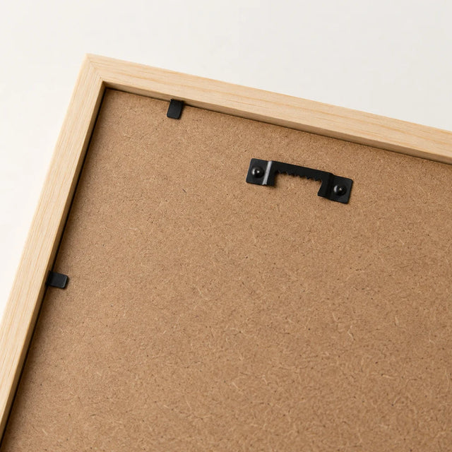 Back of a natural wood frame showing the backing board and hanging fixings