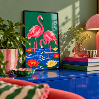 Lily Pond Flamingos Print, a small A4 framed print leaning on a colourful lacquered shelf in a living room