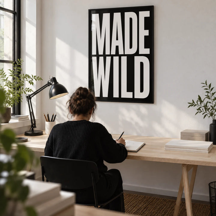 Made Wild Art Print, framed on the wall of a compact home design studio with a white wall and a wide birch plywood desk
