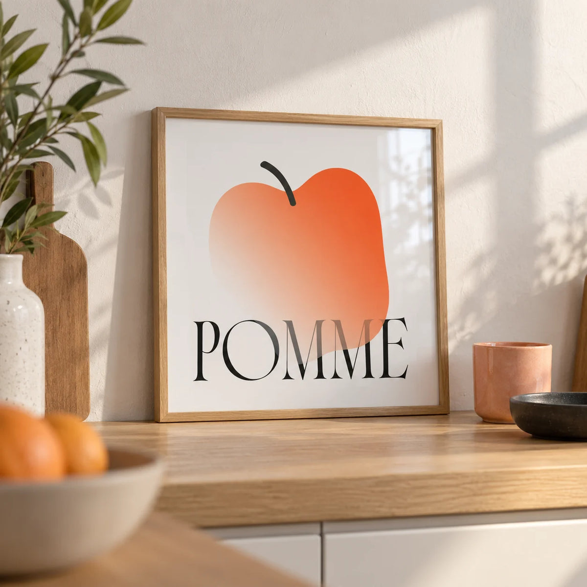 Minimalist Apple Art Print, a small A4 framed print leaning on a pale oak kitchen worktop