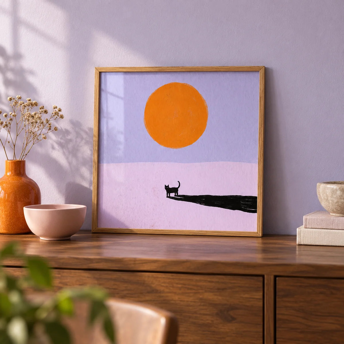 Minimalist Cat Art Print, a small A4 framed print leaning on a walnut sideboard in a living room