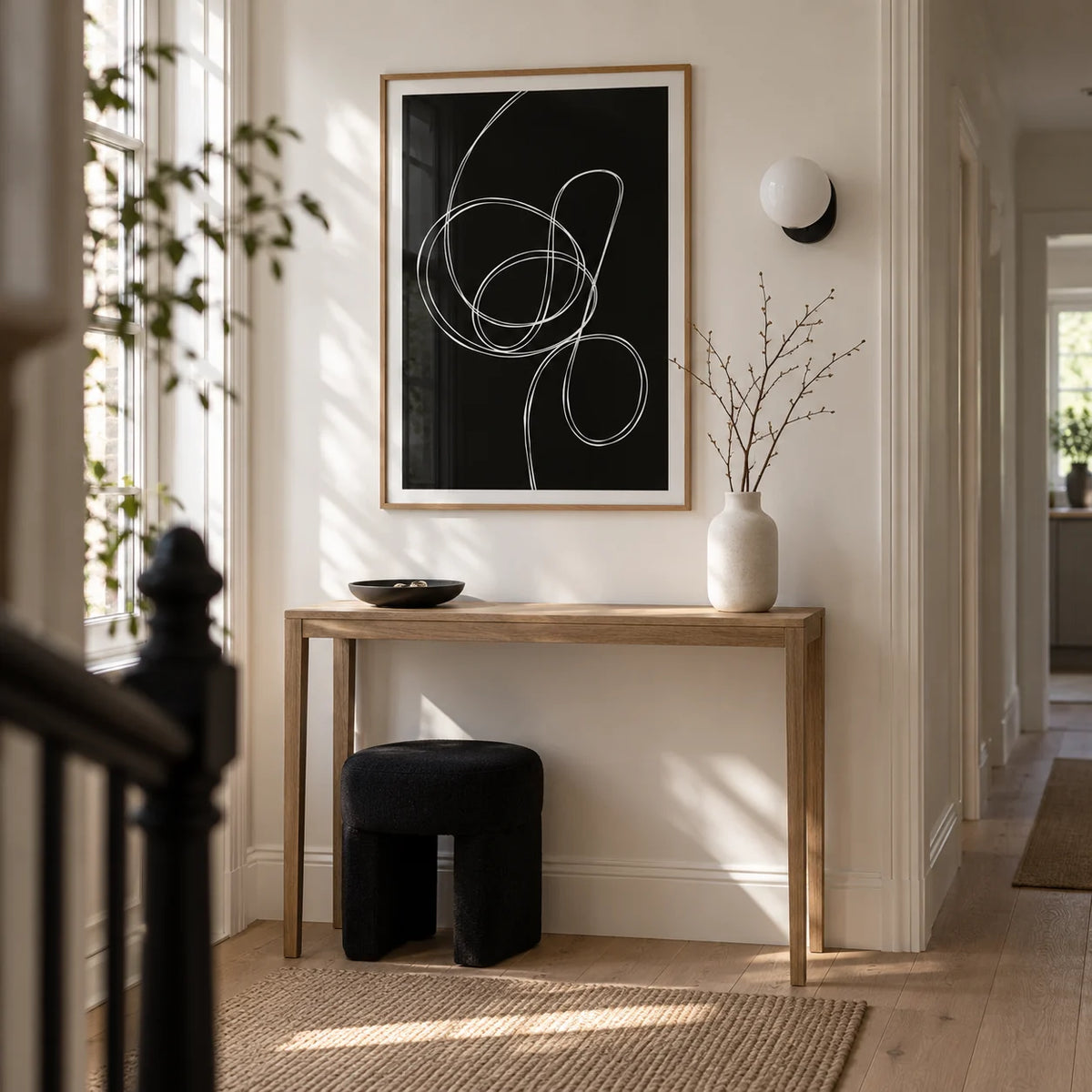 Modern Black And White Art, framed on the wall of a carefully furnished narrow hallway in a modern UK terrace with white walls and a pale oak floor