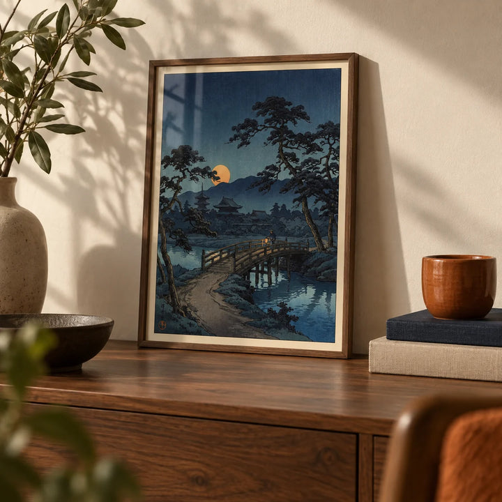 Moonlit Bridge Art Print, a small A4 framed print leaning on a walnut shelf in a living room