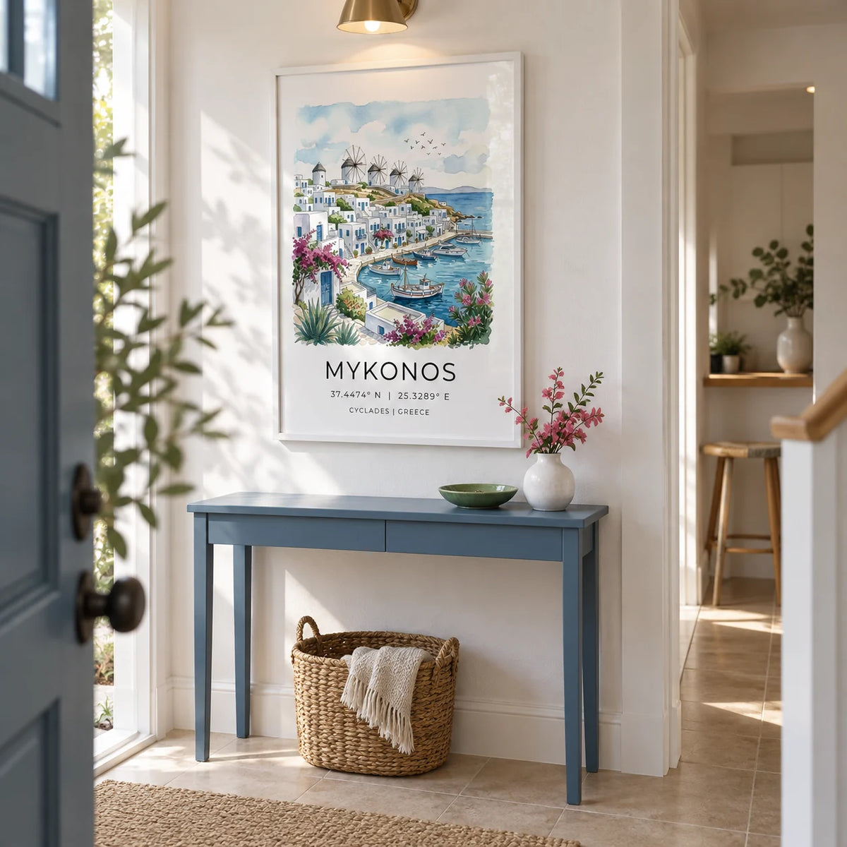 Mykonos Art Print, framed on the wall of a welcoming narrow hallway in a UK first home with white plaster walls and pale stone floor tiles