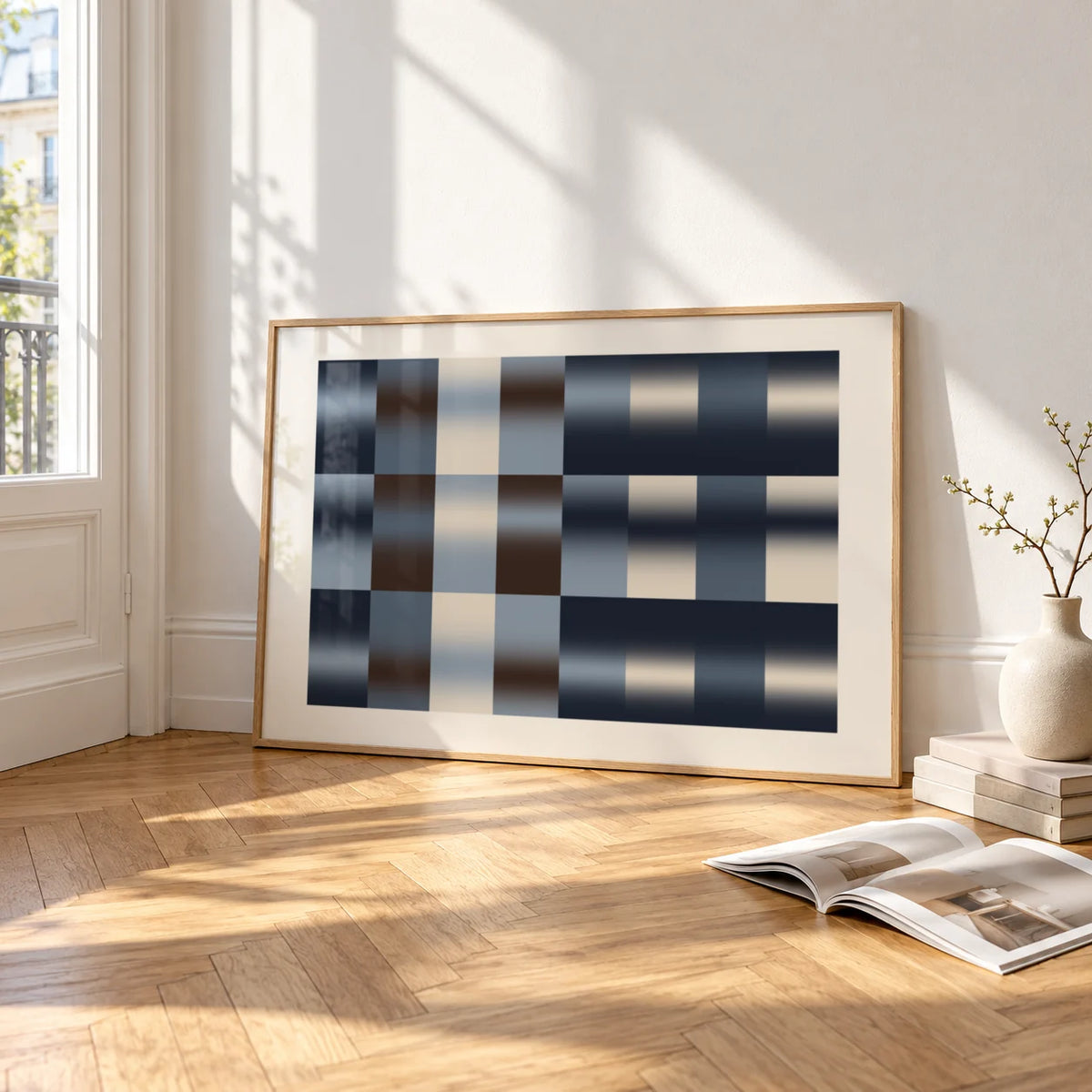 Navy Abstract Wall Art, framed and leaning on the parquet floor of a bright living room