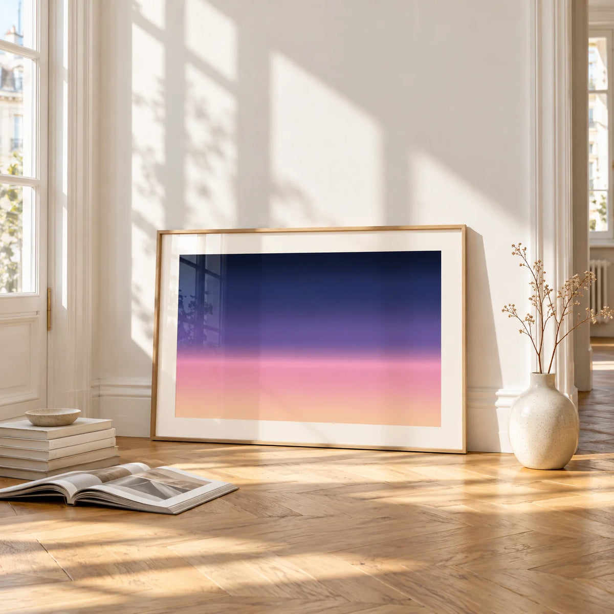 Navy and Pink Wall Art, framed and leaning on the parquet floor of a bright living room