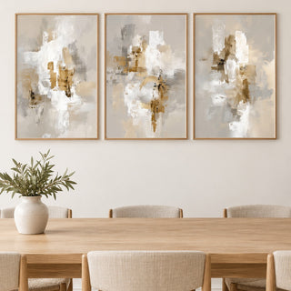 Neutral dining room wall art hung at eye level above a dining table: Neutral Brushstrokes, Modern Gold Abstract and Neutral Abstract Print shown framed side by side (frames not included)