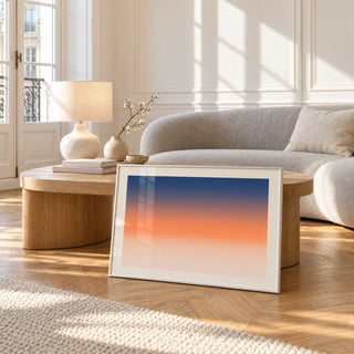 Ocean Sunset Poster, framed and leaning against a coffee table in a bright living room