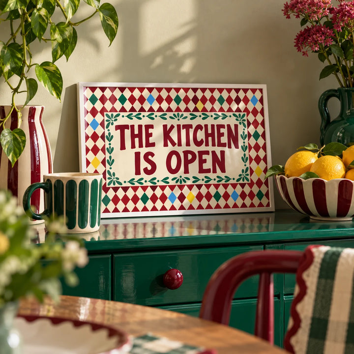 Open Kitchen Harlequin Print, a small A4 framed print leaning on a colourful lacquered shelf in a living room