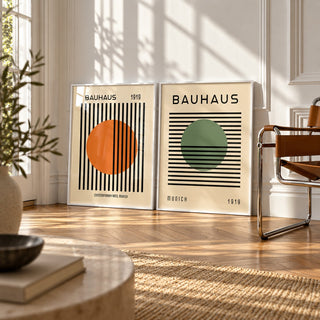 Orange and Green Wall Art Set of 2 styled leaning against a white wall beside a chrome and cognac leather sling chair: Striped Sun and Modern Orb shown framed side by side (frames not included)