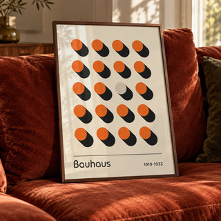 Orange Poster, a framed print leaning on a velvet sofa in a living room