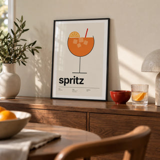 Orange Spritz Print, a small A4 framed print leaning on a walnut sideboard in a dining room