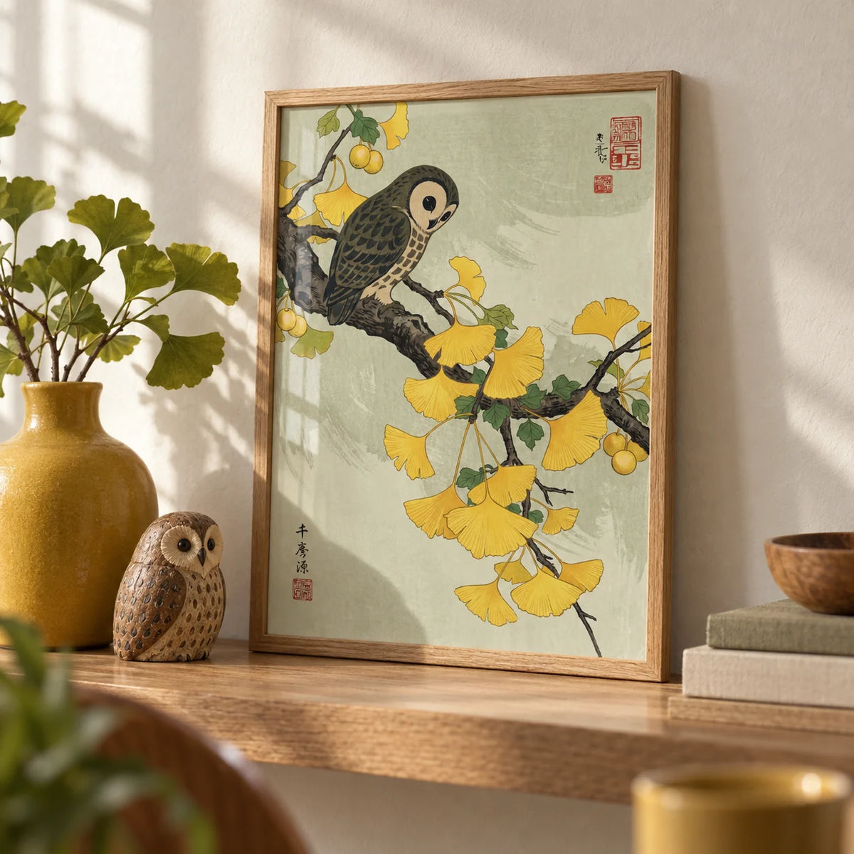 Owl and Ginkgo Print, a small A4 framed print leaning on an oak shelf in a living room