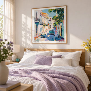 Paintings of Cuba, framed on the wall of a relaxed bedroom with a soft white wall