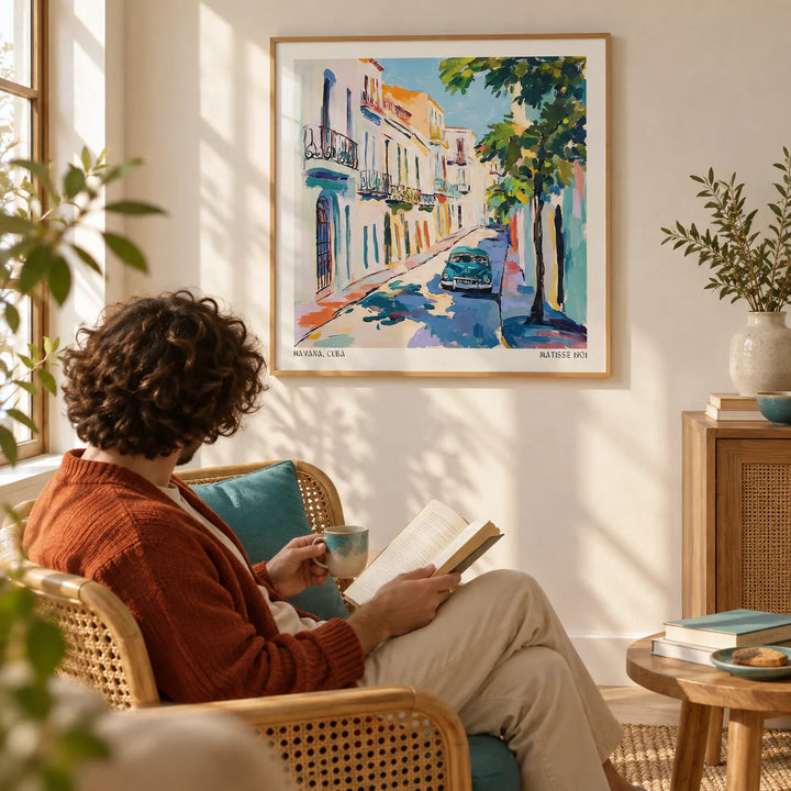 Paintings of Cuba, framed on the wall of a sunny reading spot with a warm white wall in a living room