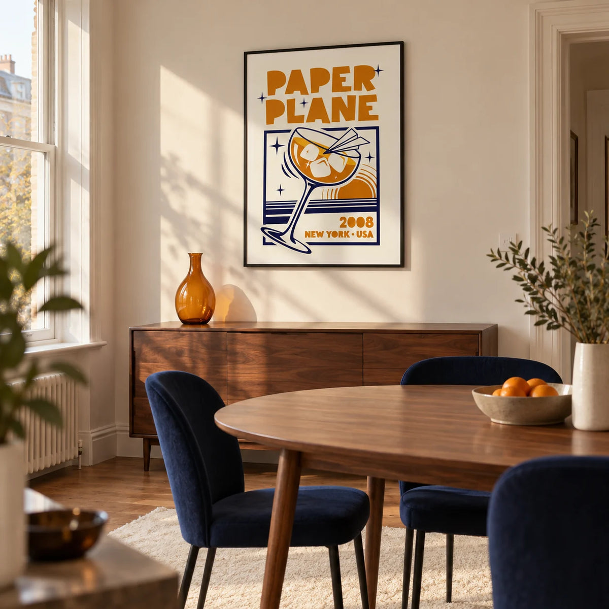 Paper Plane Cocktail Poster, framed on the wall of a design-led dining room in a British terraced house with ivory plaster walls and a walnut oval dining table