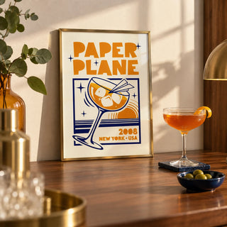 Paper Plane Cocktail Poster, a small A4 framed print leaning on a walnut home bar worktop in a kitchen