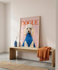 Framed picture of a dog wearing a blue sweater with 'DOGUE' text on a wall above a wooden bench.
