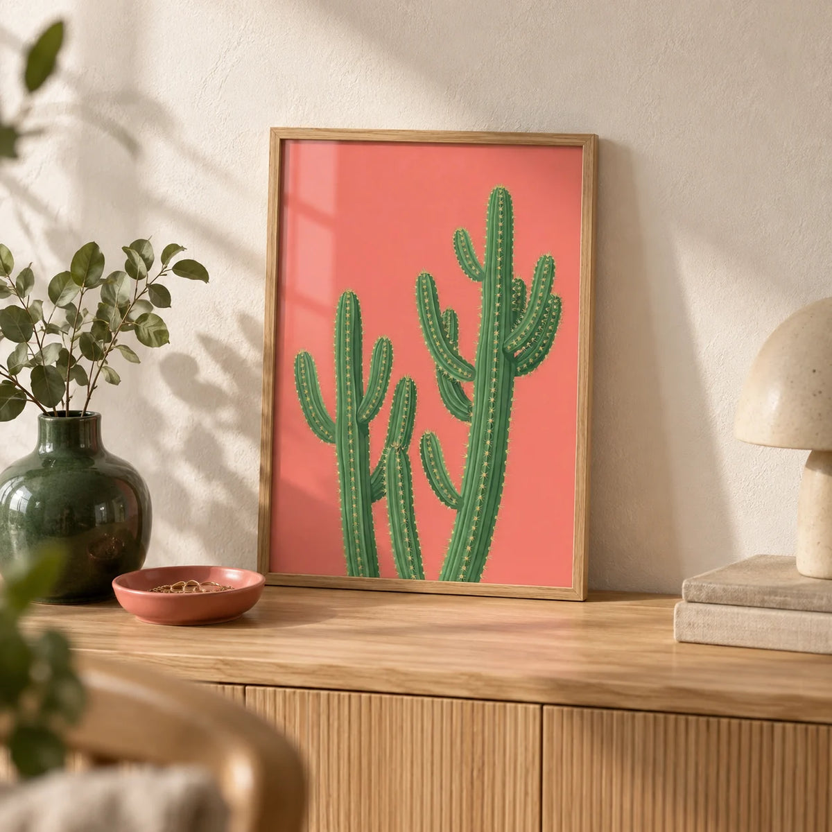 Pink Cactus Painting, a small A4 framed print leaning on a pale oak sideboard in a living room