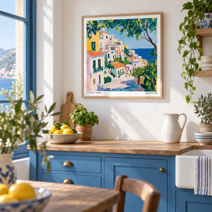Positano Art, framed on the wall of a bright Mediterranean kitchen with sea blue painted cabinets and a white wall