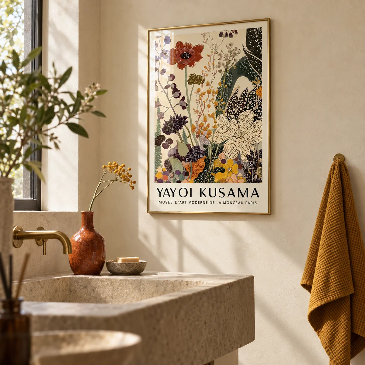 Poster Yayoi Kusama, framed on the wall of a calm bathroom with warm cream plaster walls and a plain stone basin