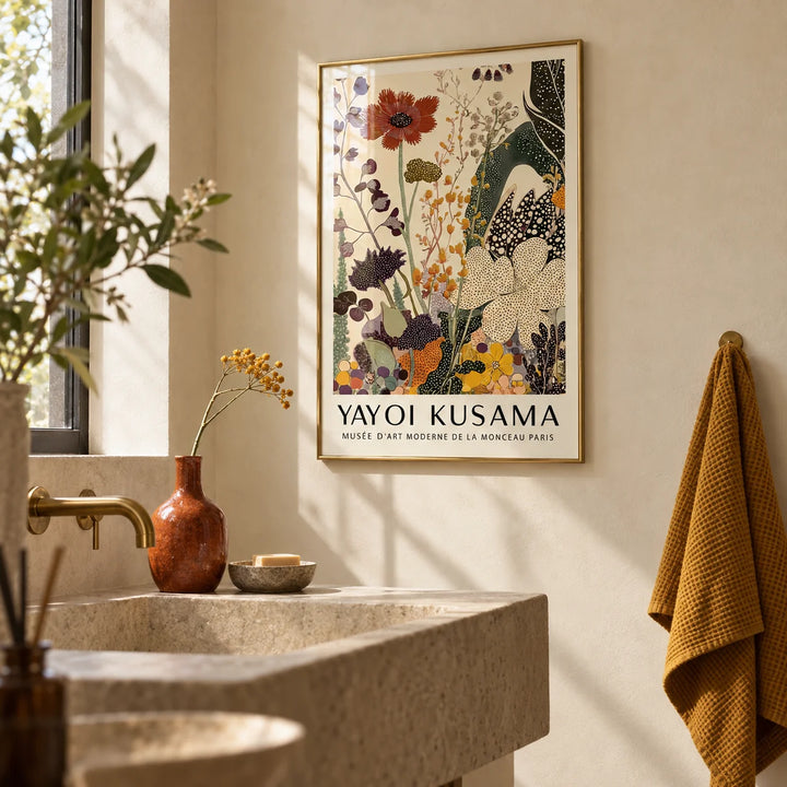 Poster Yayoi Kusama, framed on the wall of a calm bathroom with warm cream plaster walls and a plain stone basin